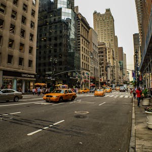 A lively street view of Midtown Manhattan capturing iconic yellow taxis and tall buildings.